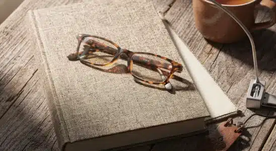 Cozy gift collection for book lovers including a novel, tea mug, reading light, and bookmark on a wooden table