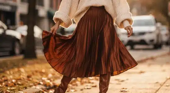 Woman wearing a pleated satin midi skirt and cream sweater for fall